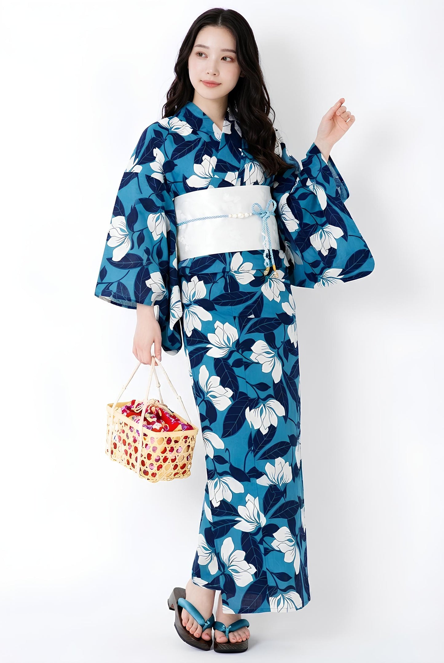 May include: A blue yukata with a white floral pattern and a white obi. The traditional Japanese garment features wide sleeves and is worn with wooden sandals. A woven basket is held in the hand.