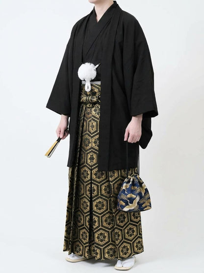 May include: A traditional Japanese formal outfit, featuring a black kimono jacket and hakama pants with a gold and black geometric pattern. A small blue bag with a crane design and a fan complete the ensemble.