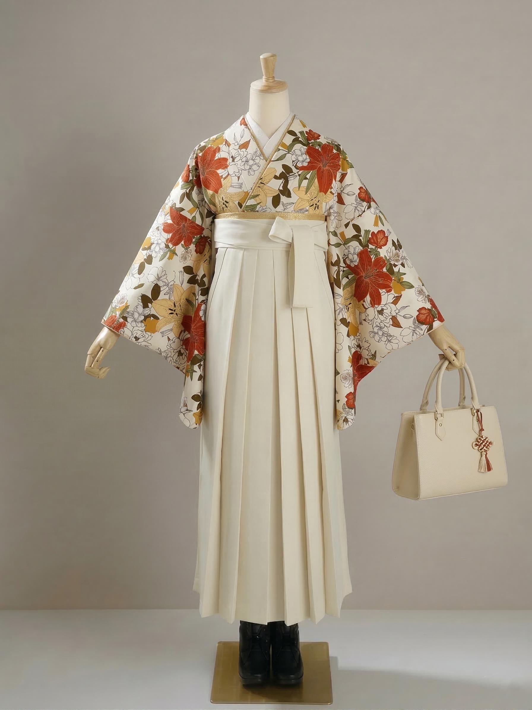 May include: A traditional Japanese hakama outfit displayed on a mannequin. The outfit includes a cream-colored pleated skirt, a floral kimono with red and yellow flowers, and a cream-colored handbag with a decorative charm.